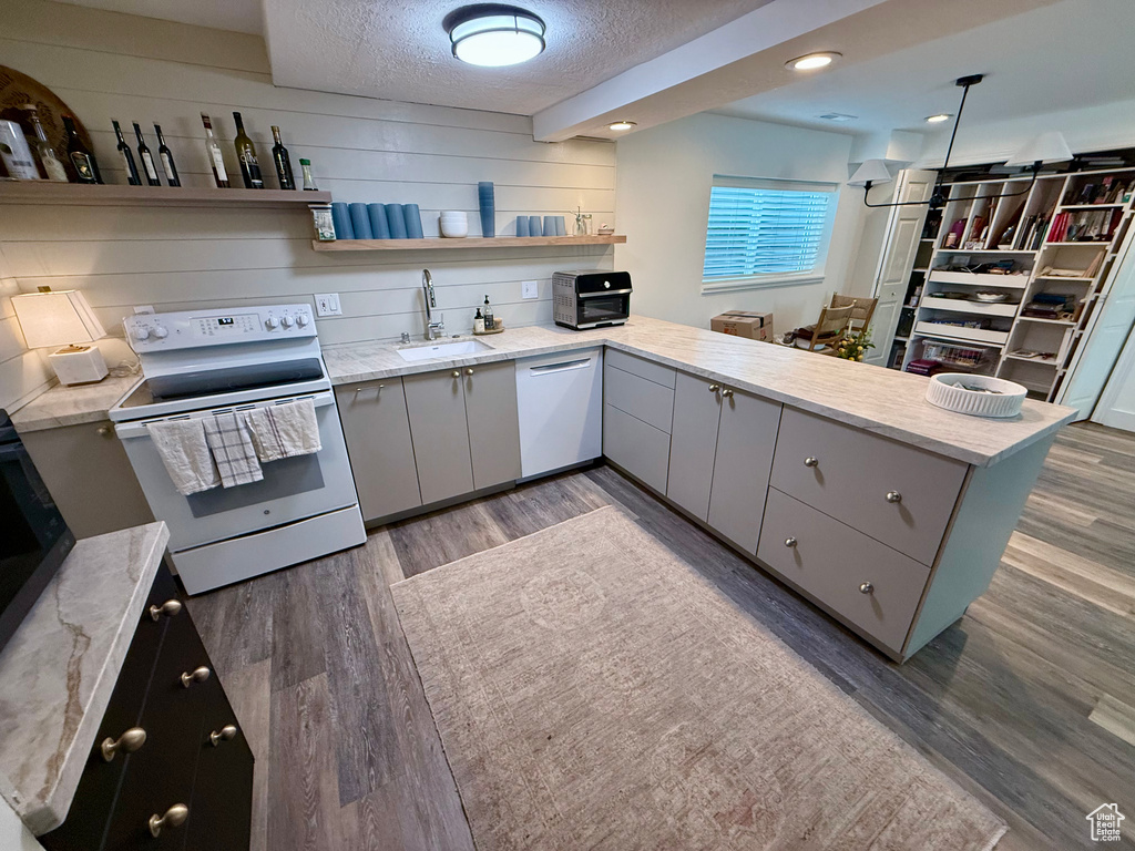 Kitchen with white appliances, gray cabinets, open shelves, a sink, and a peninsula