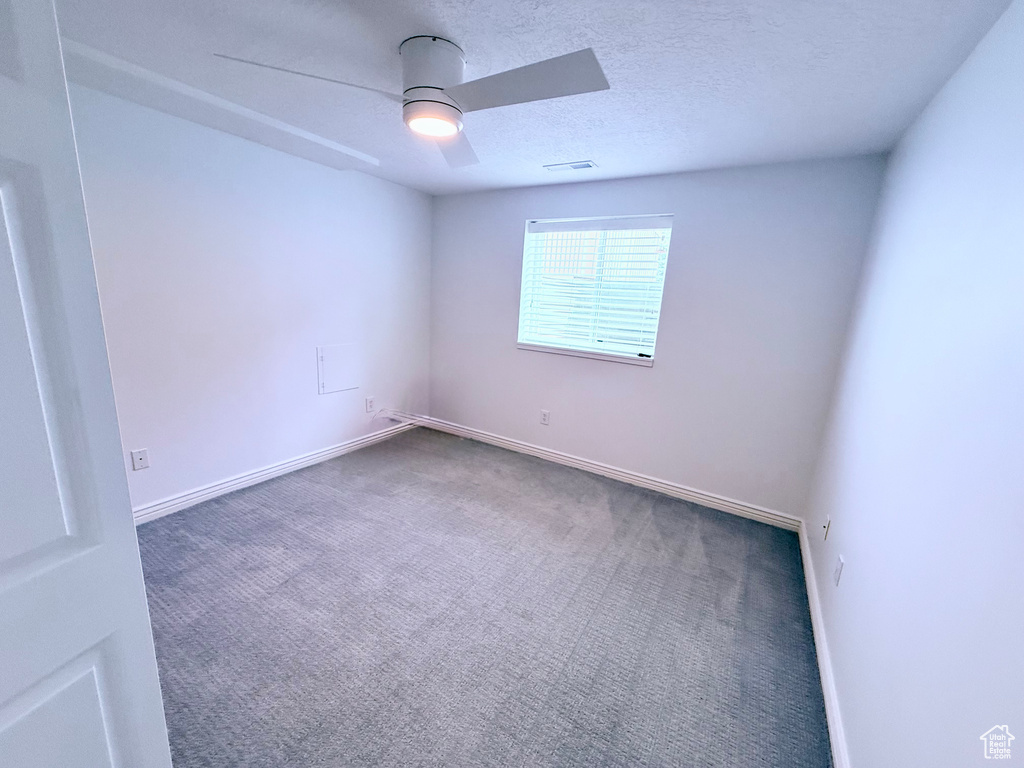 Spare room with carpet flooring, a ceiling fan, baseboards, and a textured ceiling