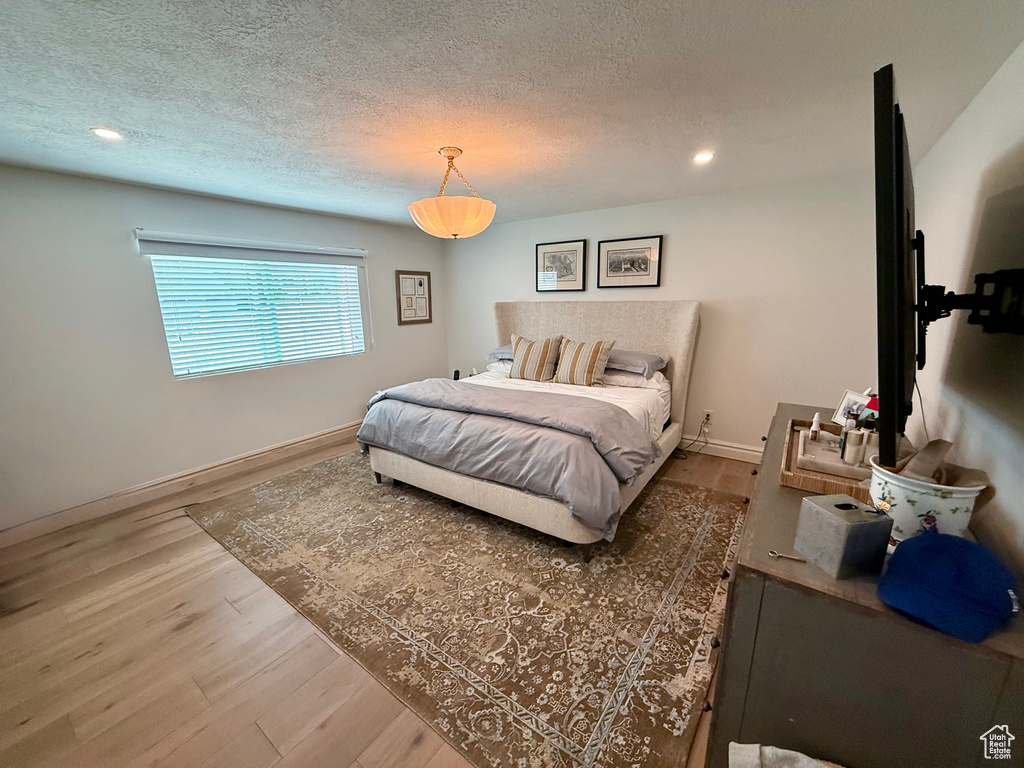 Bedroom with wood finished floors, a textured ceiling, recessed lighting, and baseboards