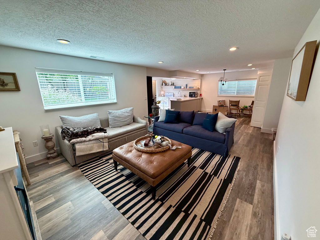 Living room with wood finished floors, healthy amount of natural light, recessed lighting, a textured ceiling, and baseboards