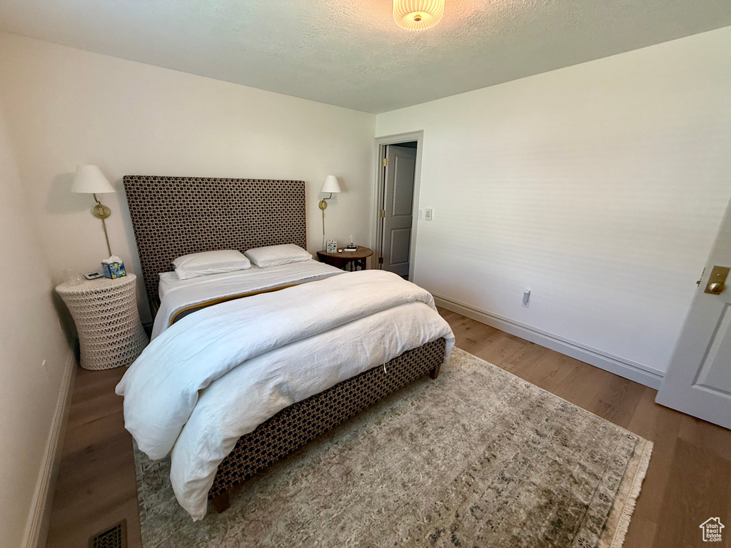 Bedroom with baseboards, wood finished floors, and a textured ceiling