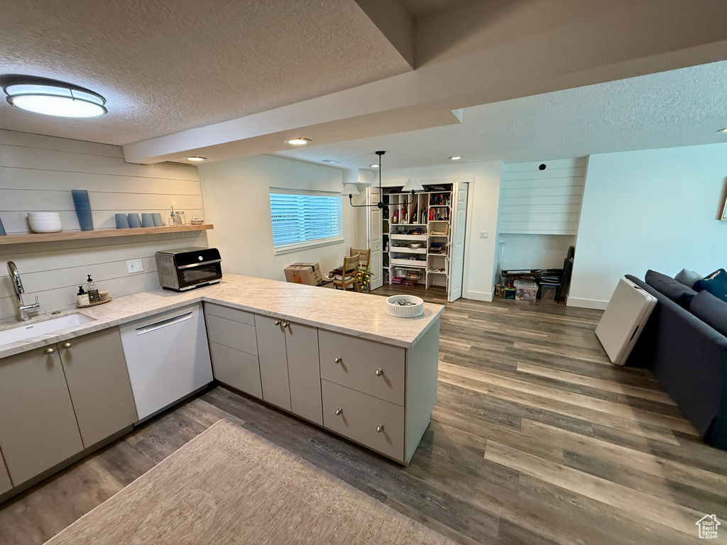 Kitchen with a sink, white dishwasher, a textured ceiling, gray cabinetry, and a peninsula