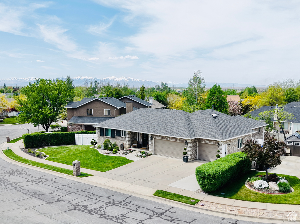 View of front of house with a garage, driveway, stone siding, and a residential view