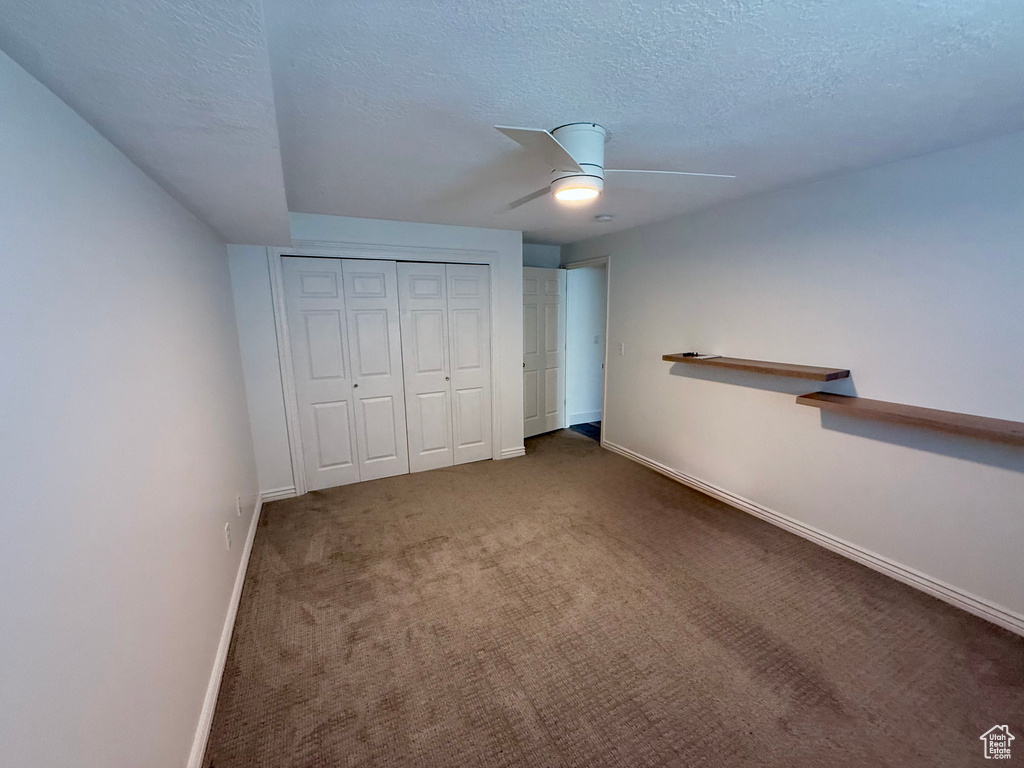 Unfurnished bedroom with baseboards, a textured ceiling, carpet flooring, a closet, and a ceiling fan