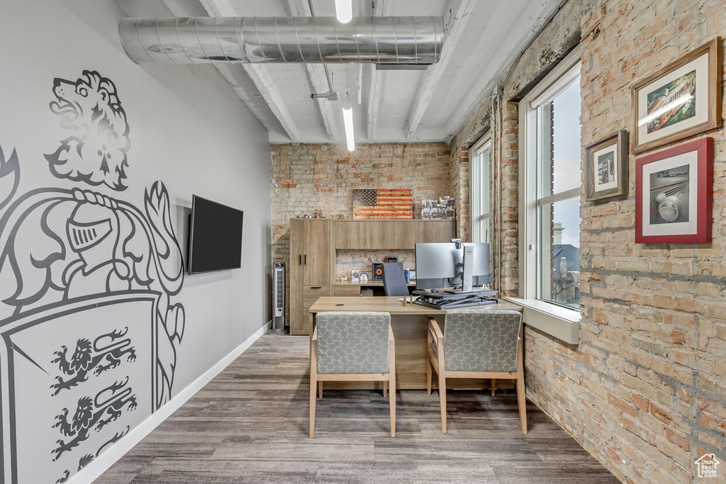 Office area featuring brick wall, wood finished floors, beam ceiling, and baseboards