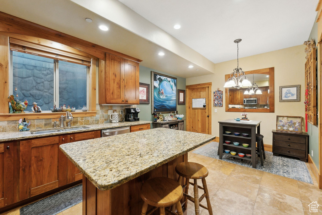 Kitchen featuring a sink, recessed lighting, appliances with stainless steel finishes, a kitchen island, and brown cabinetry
