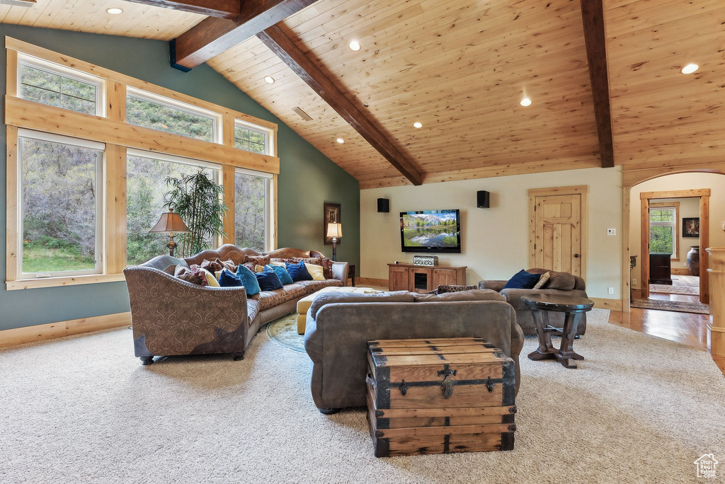 Living area featuring beam ceiling, arched walkways, carpet, recessed lighting, and high vaulted ceiling