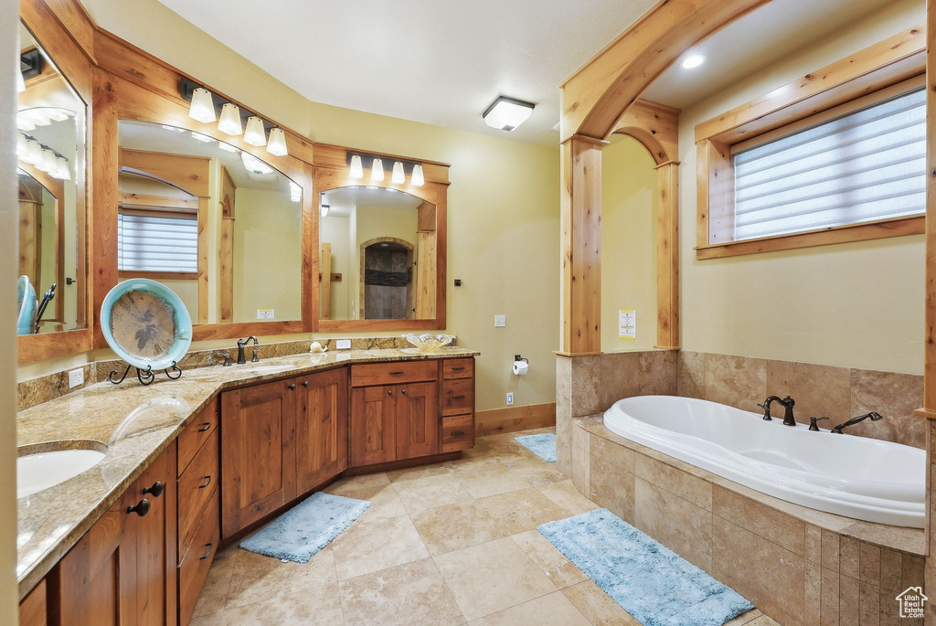 Full bathroom with a bath, double vanity, baseboards, and tile patterned flooring