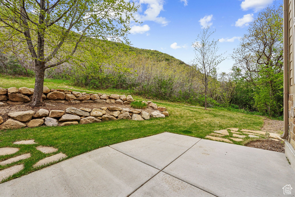 View of grassy yard featuring a patio area and a mountain view