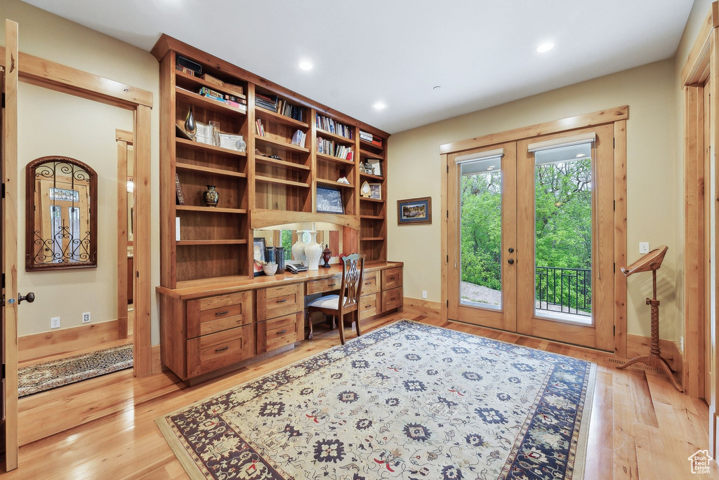 Home office with built in study area, french doors, light wood-style floors, recessed lighting, and baseboards