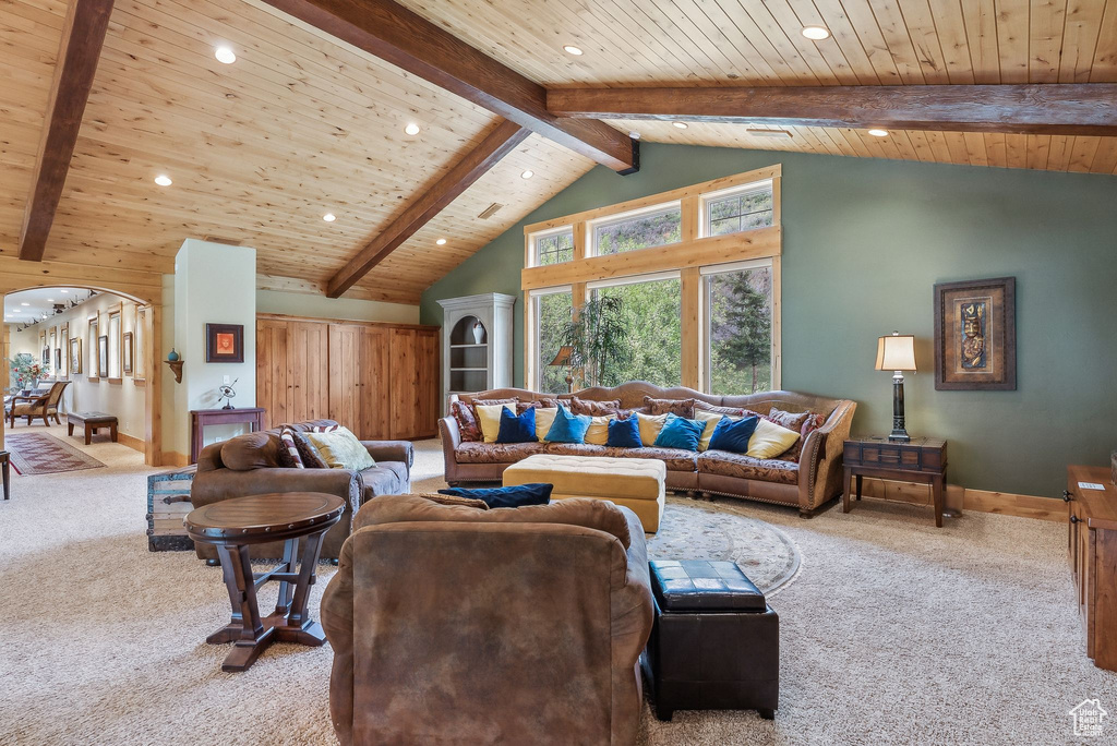 Carpeted living room with wood ceiling, beam ceiling, recessed lighting, arched walkways, and baseboards
