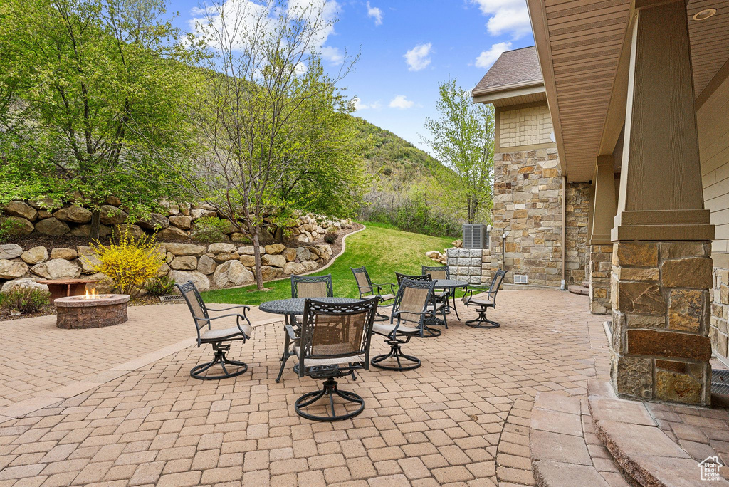 View of patio with an outdoor fire pit, outdoor dining area, a mountain view, and central air condition unit
