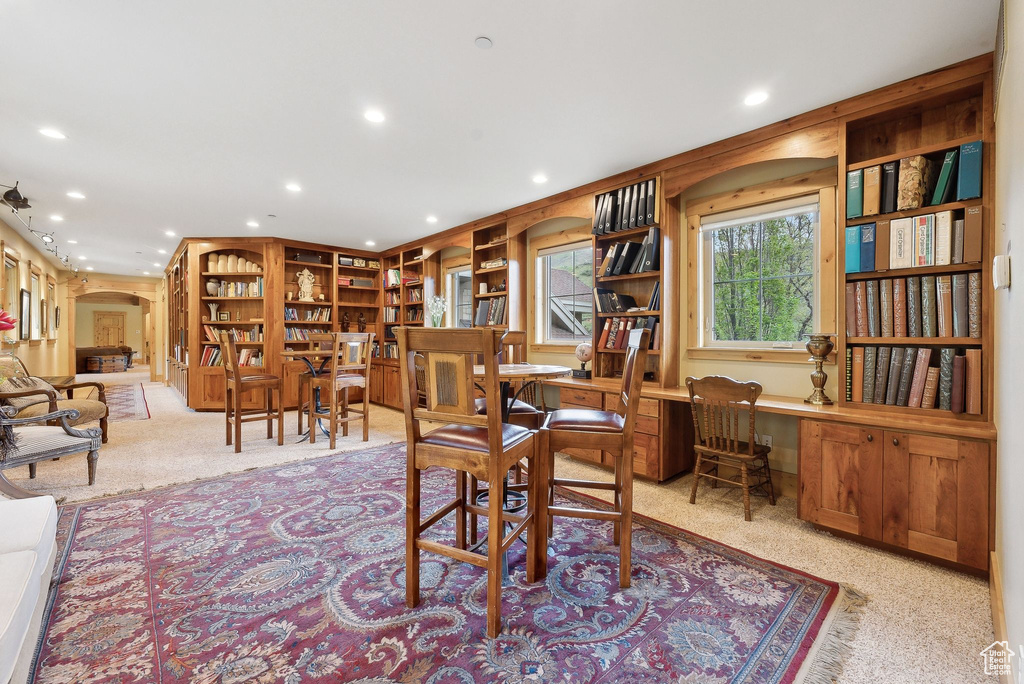 Carpeted dining space with arched walkways and recessed lighting