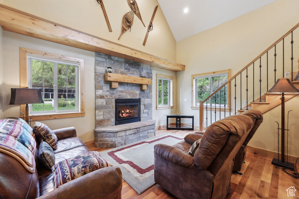 Living room with hardwood / wood-style flooring, healthy amount of natural light, a fireplace, high vaulted ceiling, and stairs