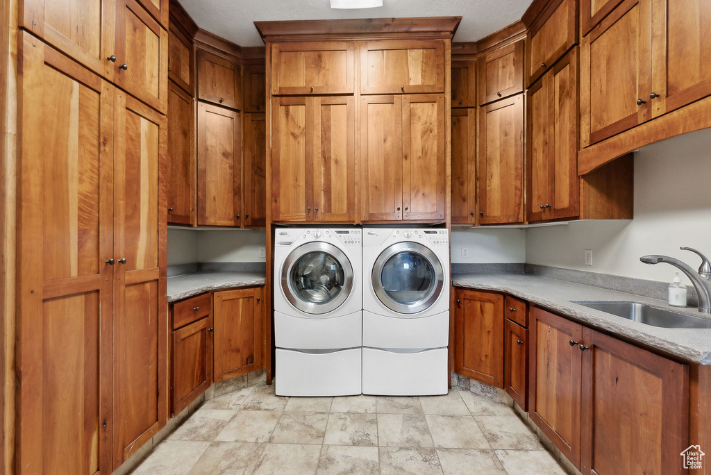 Washroom with cabinet space, separate washer and dryer, and light stone finish flooring