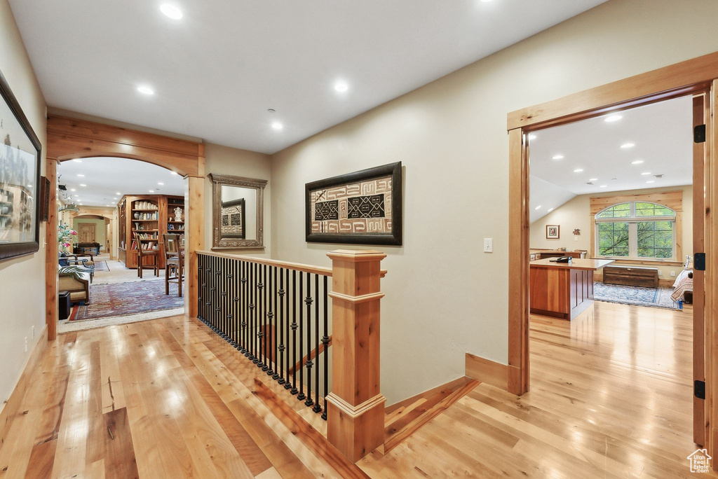 Hallway featuring arched walkways, hardwood / wood-style floors, recessed lighting, an upstairs landing, and baseboards