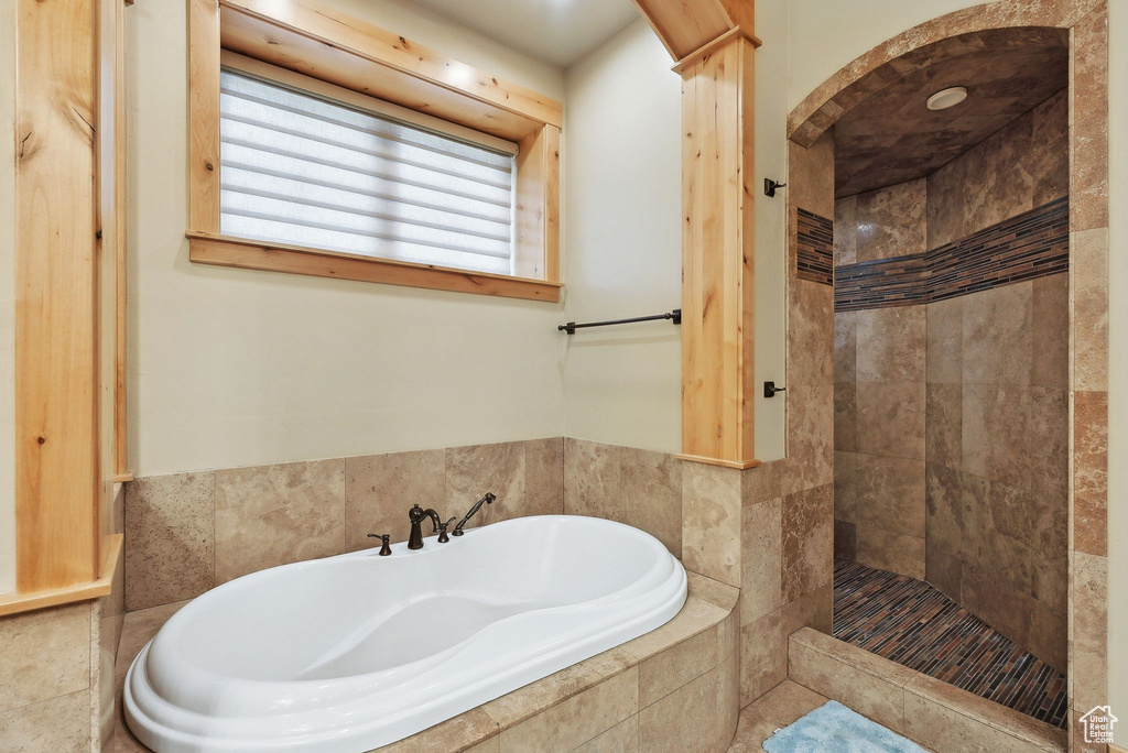 Bathroom featuring a bath and a tile shower