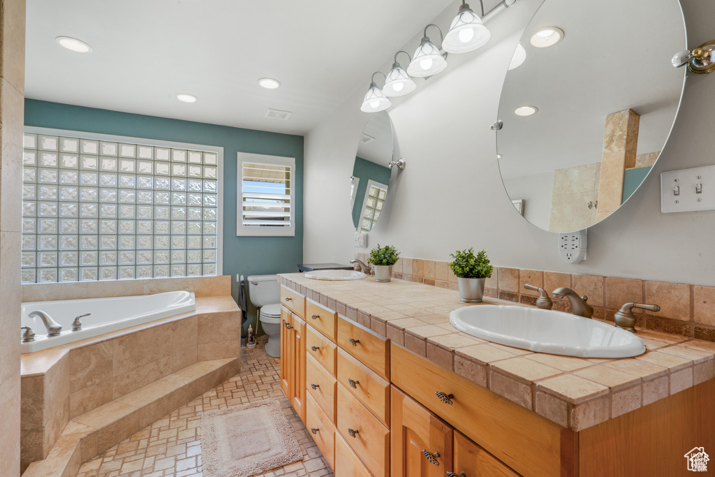 Full bath with a garden tub, double vanity, toilet, and recessed lighting