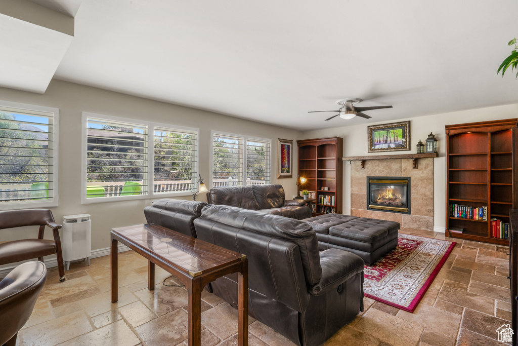 Living area with stone tile floors, ceiling fan, a tile fireplace, and baseboards