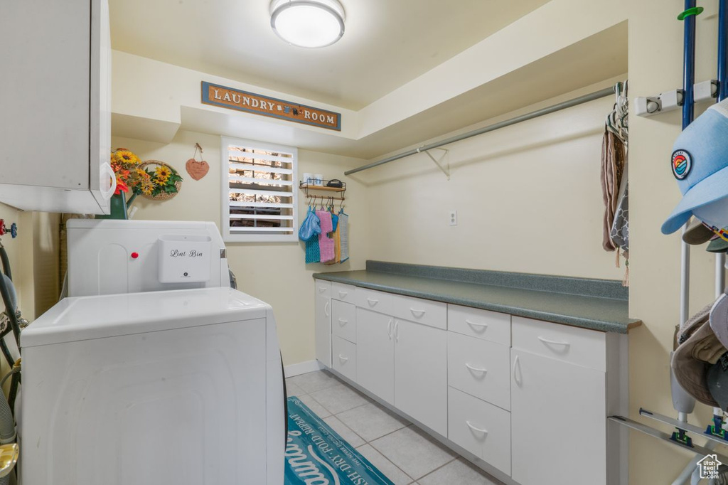 Laundry room featuring cabinet space, light tile patterned floors, and washer and clothes dryer
