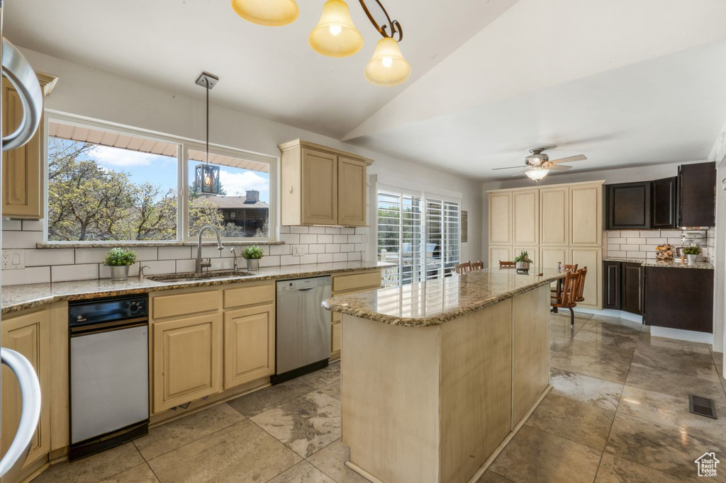 Kitchen with dishwasher, a sink, backsplash, light brown cabinets, and lofted ceiling