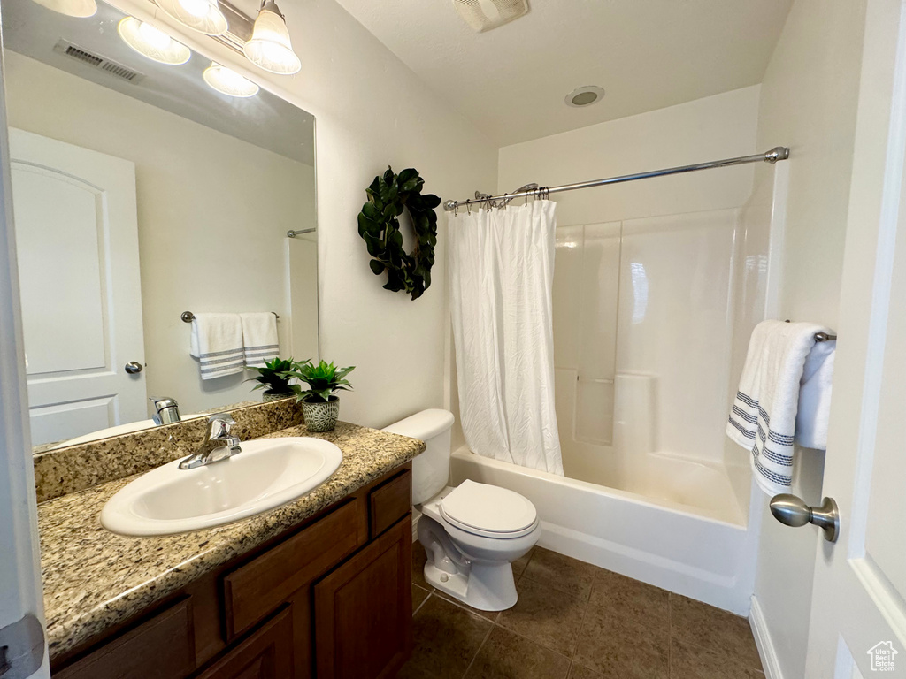 Full bathroom with tile patterned floors, shower / bath combination with curtain, vanity, and toilet