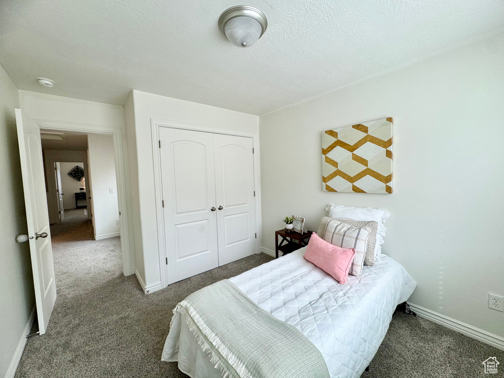 Bedroom featuring carpet, a closet, a textured ceiling, and baseboards