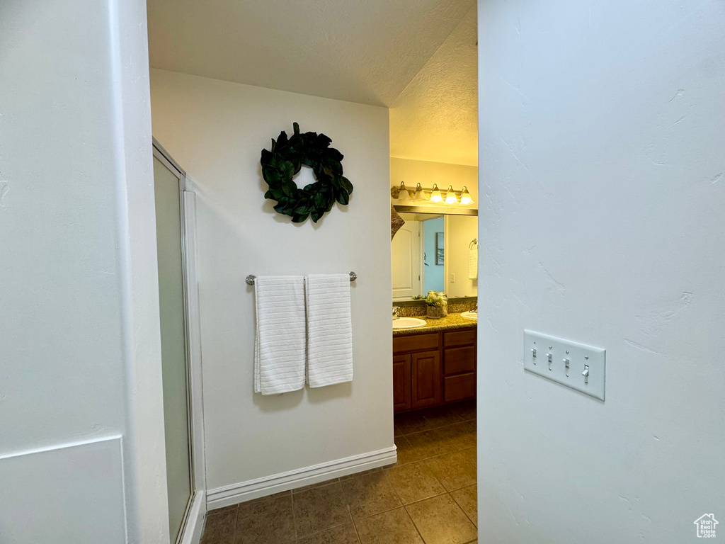 Full bathroom with tile patterned floors, a stall shower, vanity, and baseboards