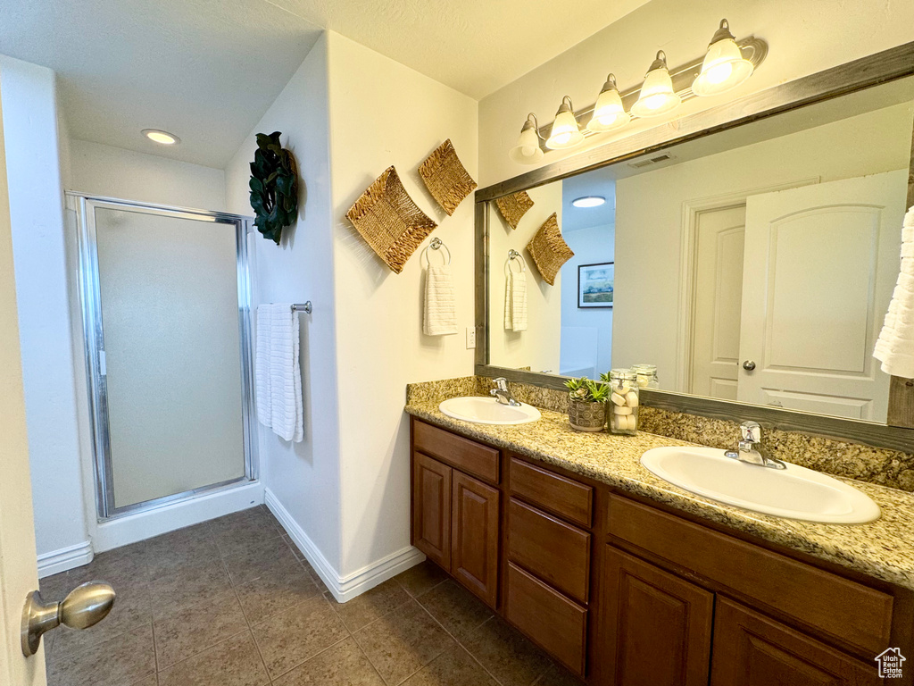 Full bathroom featuring baseboards, a stall shower, double vanity, and tile patterned flooring