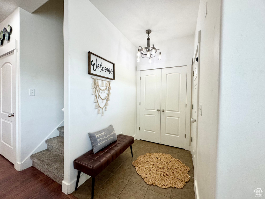 Foyer entrance featuring a chandelier, stairs, baseboards, and tile patterned floors