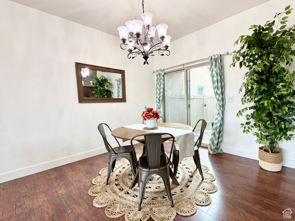 Dining room featuring baseboards, a chandelier, and dark wood-type flooring