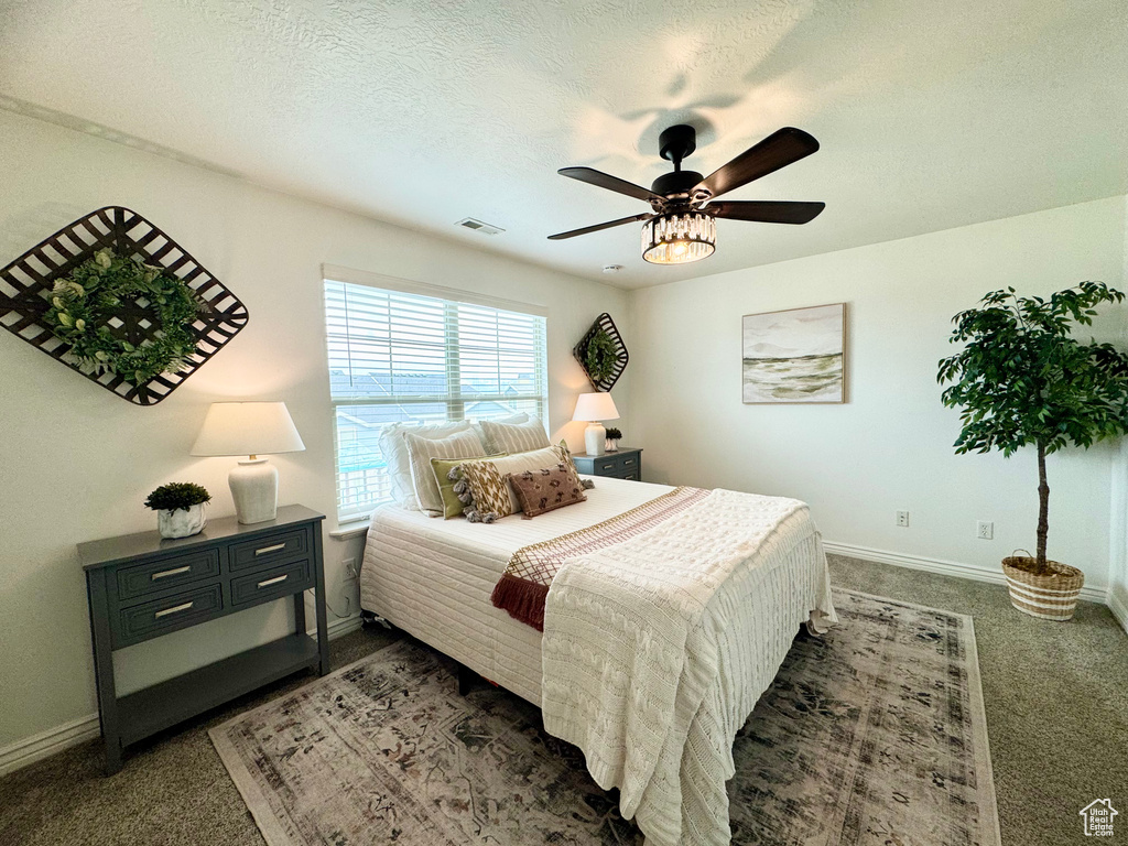 Carpeted bedroom featuring baseboards, ceiling fan, and a textured ceiling