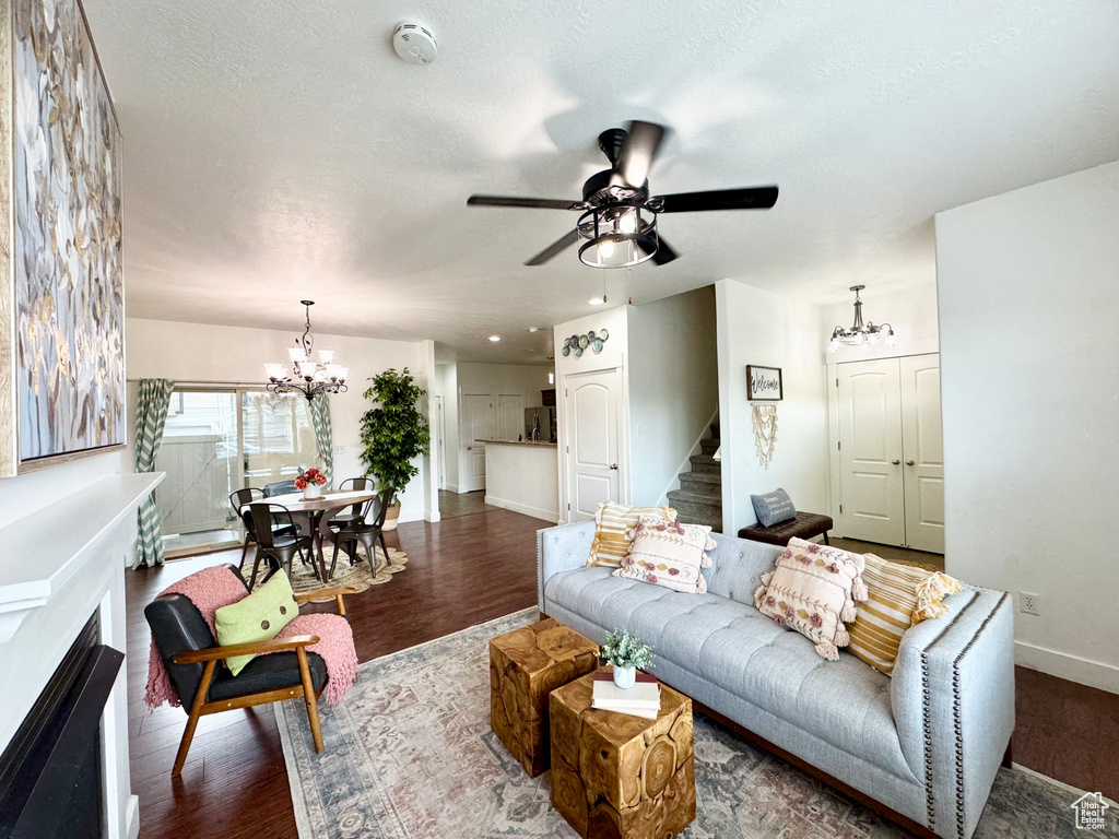 Living room featuring a chandelier, wood finished floors, baseboards, and stairs