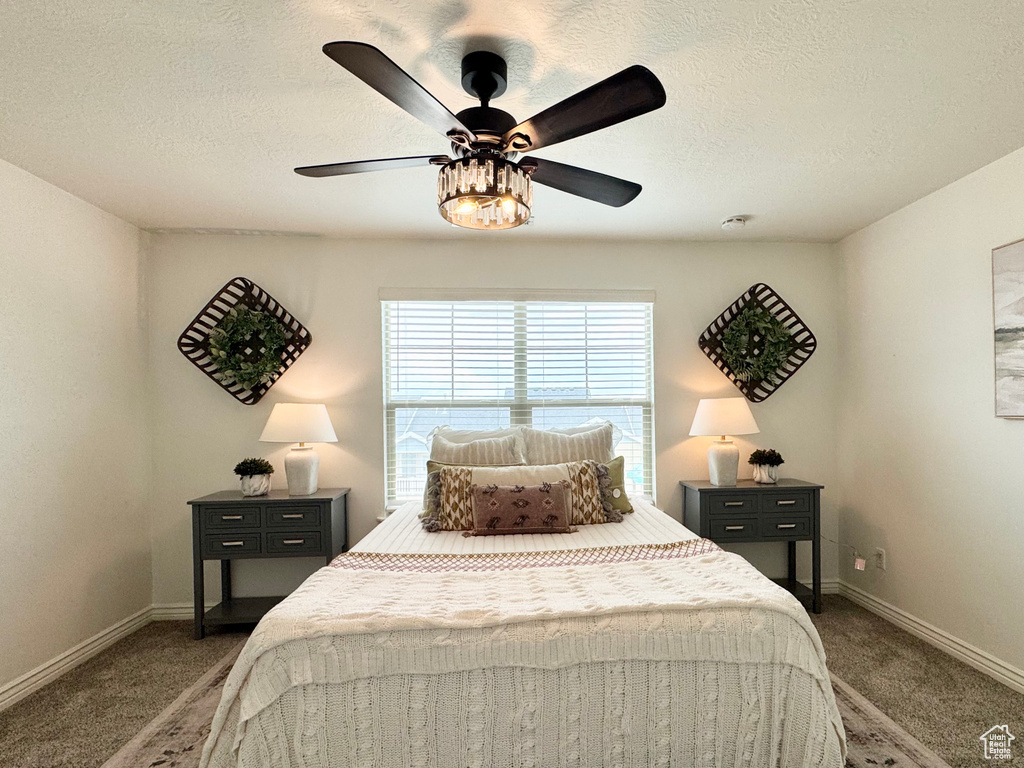 Carpeted bedroom featuring baseboards, a textured ceiling, and ceiling fan