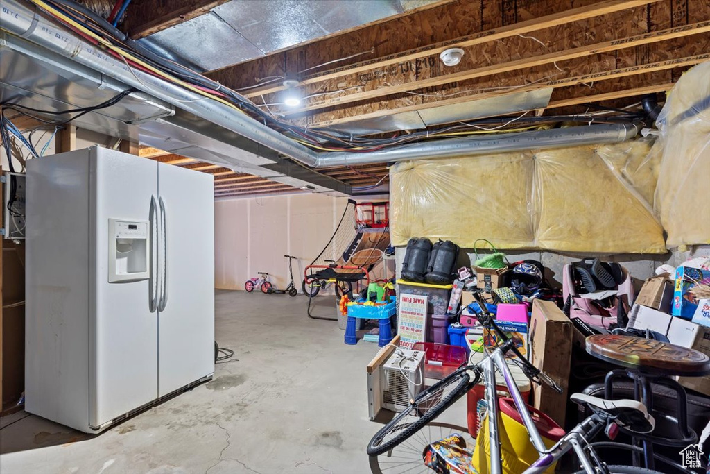 Unfinished below grade area with white fridge with ice dispenser