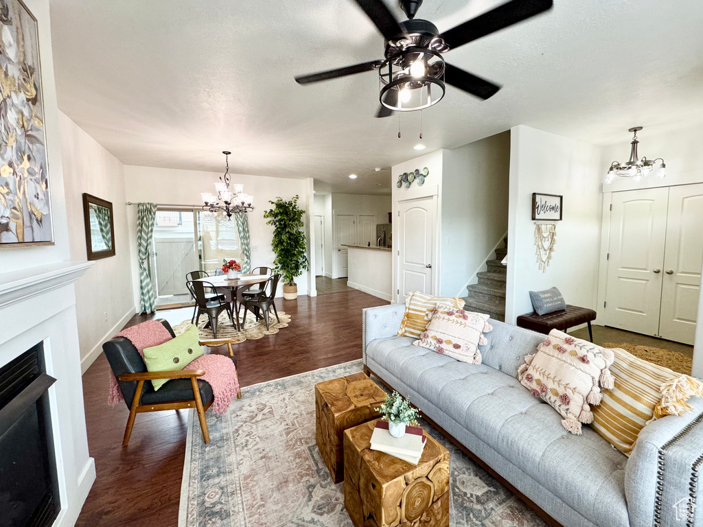 Living area featuring a chandelier, baseboards, wood finished floors, stairs, and a fireplace