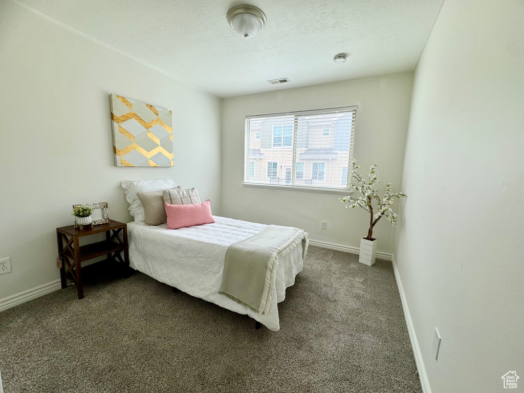 Bedroom featuring baseboards, dark colored carpet, and a textured ceiling