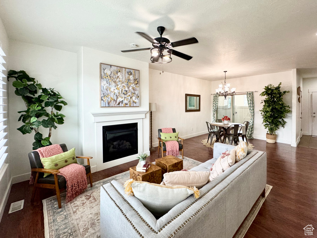 Living area with a fireplace, a chandelier, baseboards, and wood finished floors