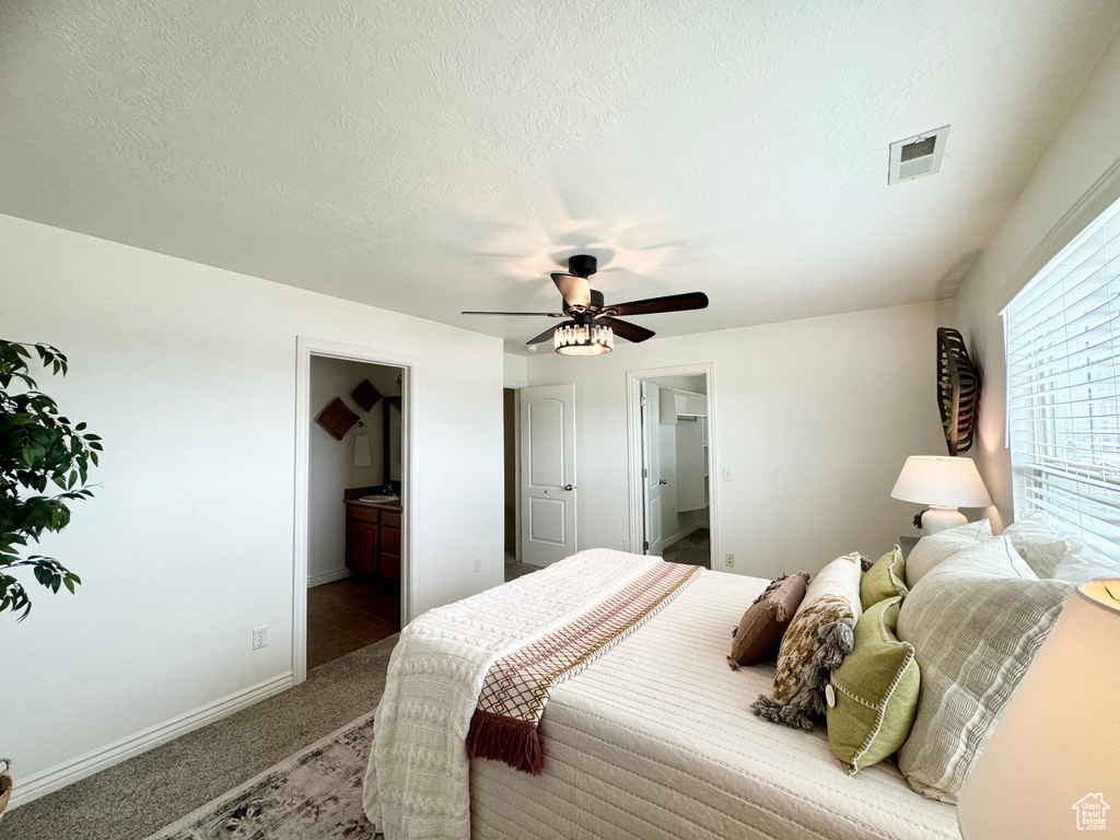 Bedroom with carpet flooring, baseboards, a ceiling fan, a spacious closet, and connected bathroom