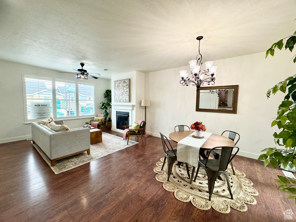 Dining area with a glass covered fireplace, dark wood finished floors, baseboards, a chandelier, and a textured ceiling