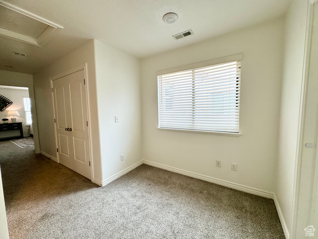 Unfurnished bedroom with carpet floors, baseboards, and attic access