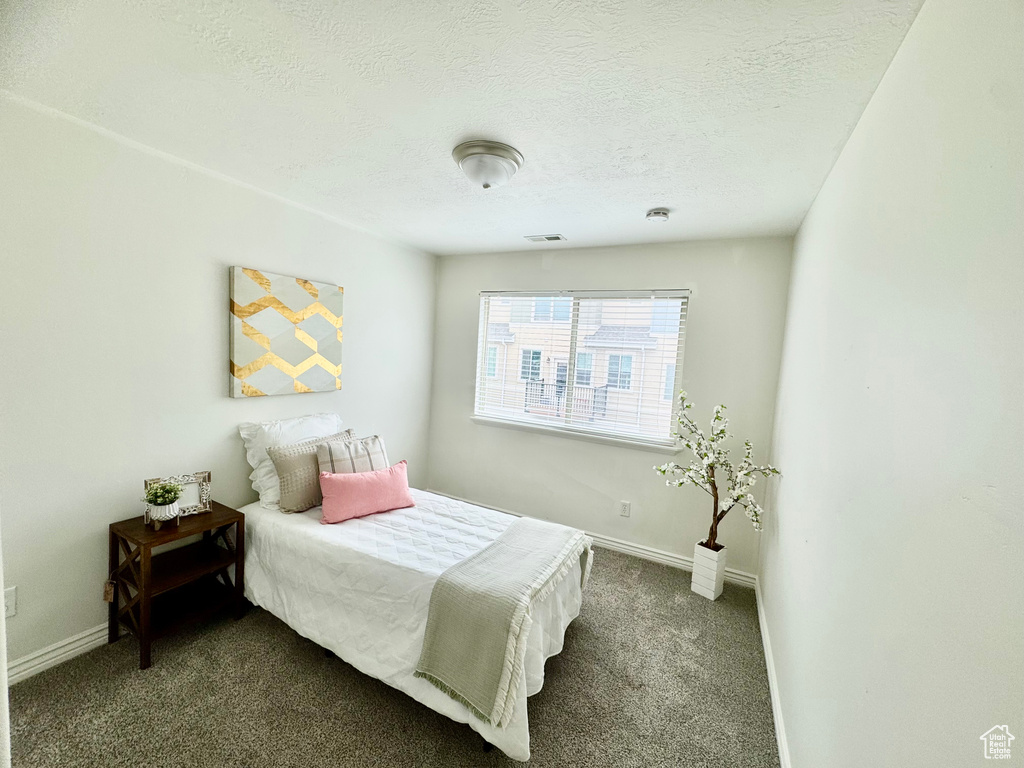 Bedroom featuring dark carpet, baseboards, and a textured ceiling