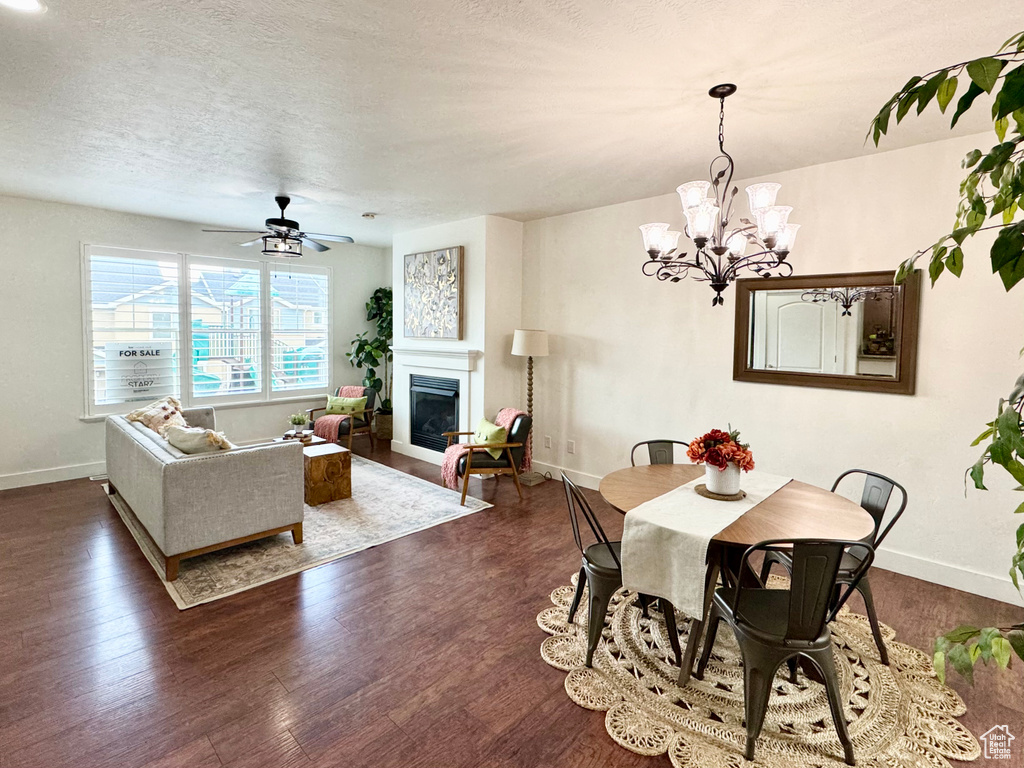 Dining space featuring a glass covered fireplace, baseboards, dark wood-style flooring, a chandelier, and a textured ceiling