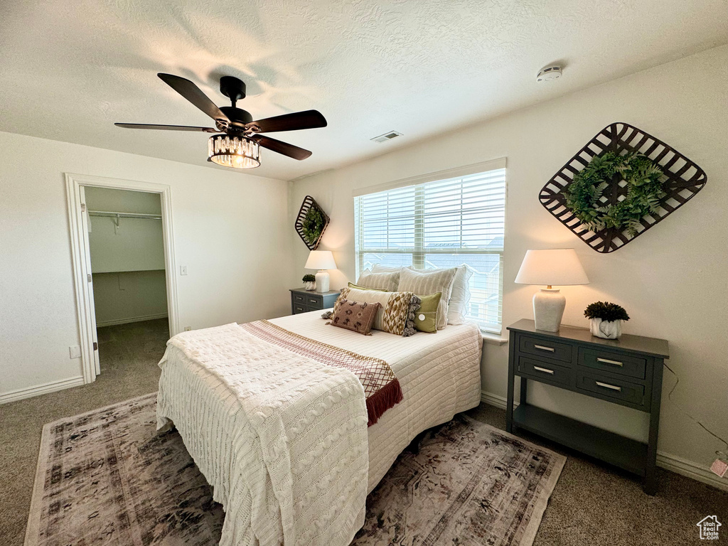 Carpeted bedroom featuring baseboards, ceiling fan, a spacious closet, and a textured ceiling