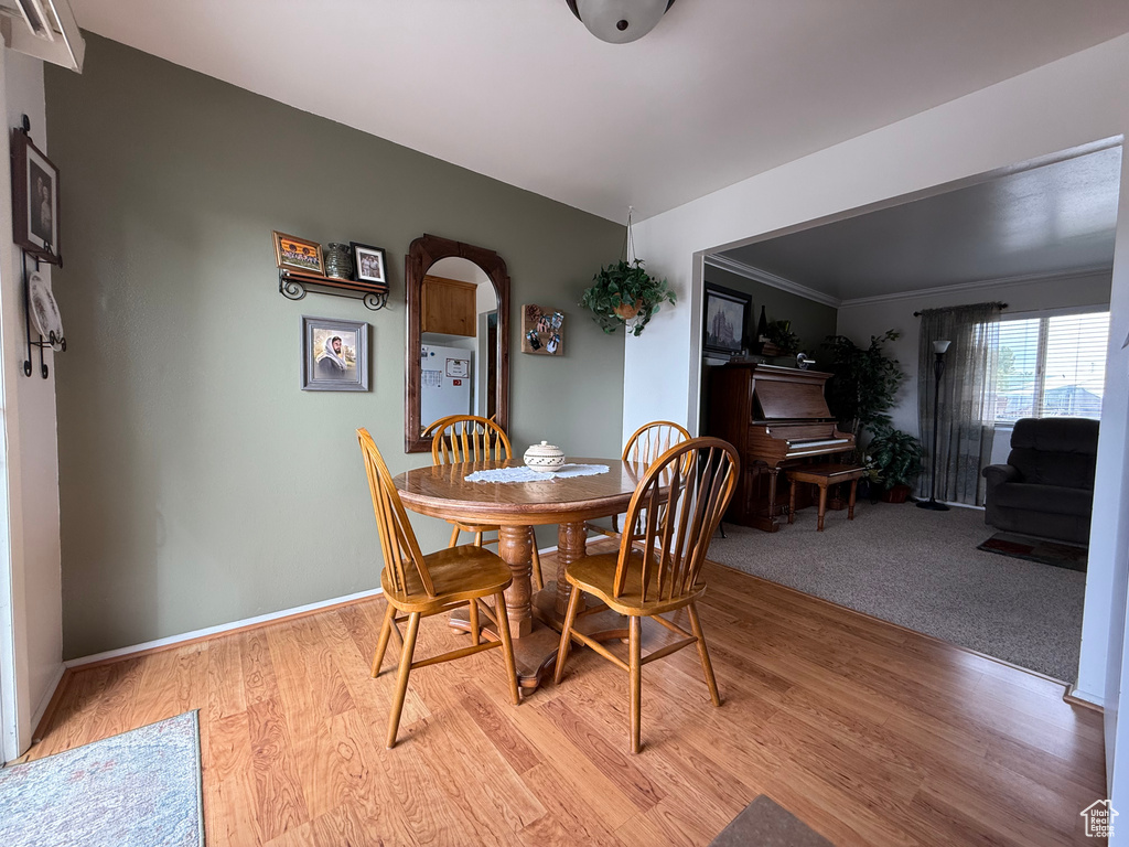 Dining space with arched walkways, light wood-style floors, and baseboards