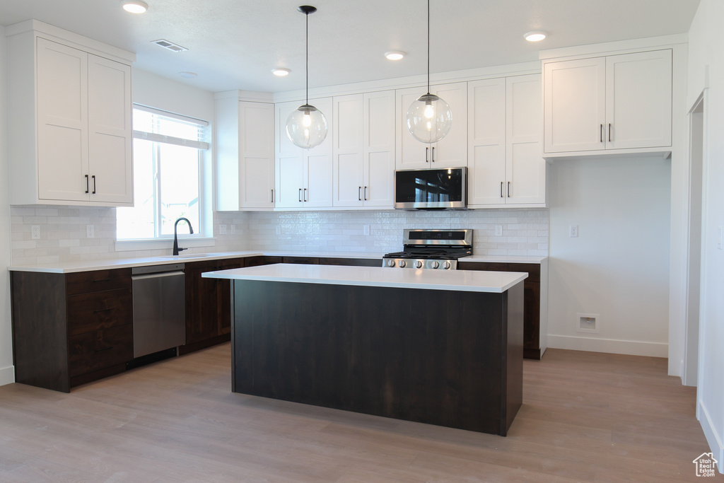 Kitchen with appliances with stainless steel finishes, light countertops, white cabinetry, a kitchen island, and recessed lighting