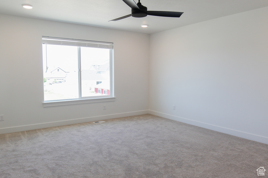 Carpeted spare room with healthy amount of natural light and ceiling fan