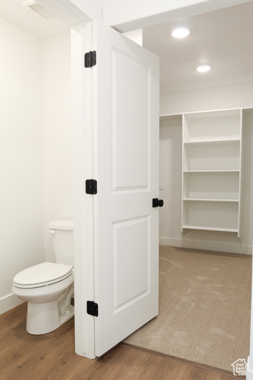 Bathroom featuring wood finished floors, toilet, recessed lighting, and baseboards