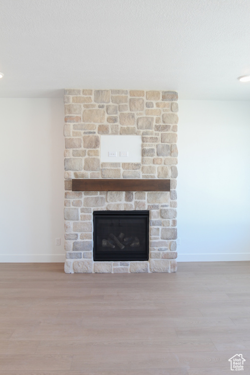 Detailed view of a fireplace, wood finished floors, and a textured ceiling