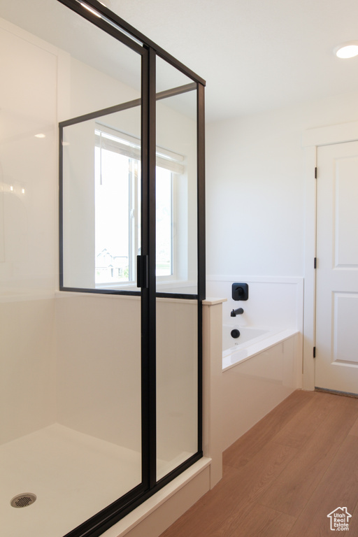 Full bath featuring wood finished floors, a shower stall, and a garden tub